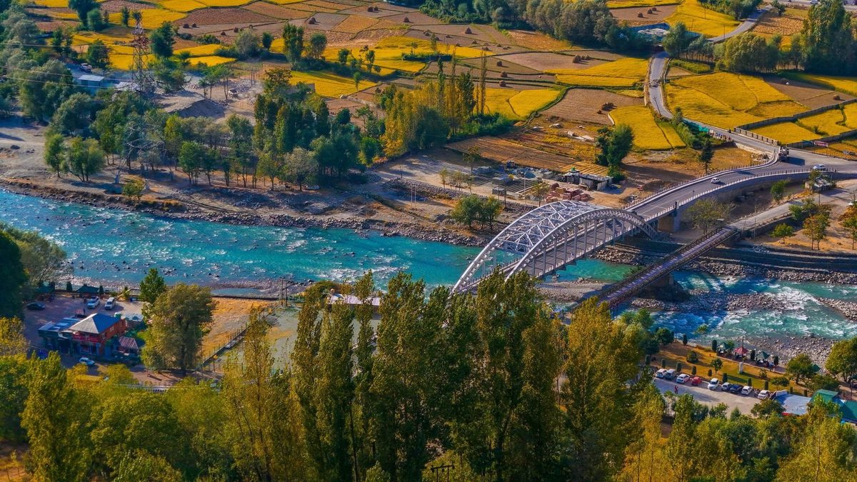 Bridge over river beside golden Kashmir fields
